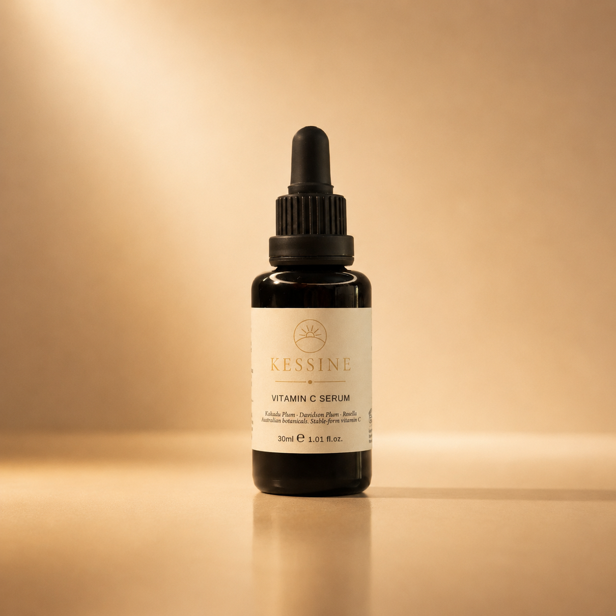 Kessine Kakadu Plum Vitamin C Serum in a 30ml amber glass dropper bottle, on a warm sand-coloured background